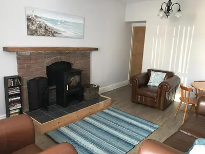 a living room with a brick fireplace and a chair at Curlew Cottage and Sunset View in Port Logan