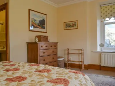 a bedroom with a bed and a dresser and a window at Middle Howe in Portinscale