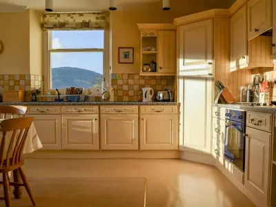 a kitchen with white cabinets and a window at Middle Howe in Portinscale