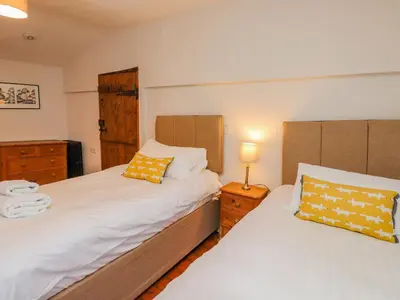 two beds in a small bedroom with two lamps at Fir Tree Cottage in Ambleside