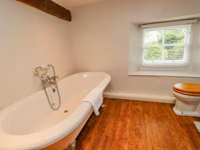 a bathroom with a white tub and a toilet at Fir Tree Cottage in Ambleside