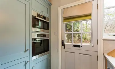 a kitchen with a door and a stove and a window at Acorn Cottage in Grasmere