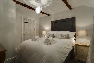 a bedroom with a white bed with towels on it at Acorn Cottage in Grasmere