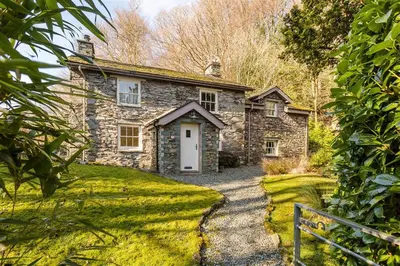 an old stone house with a white door and a driveway at Thimble Hall in Grasmere
