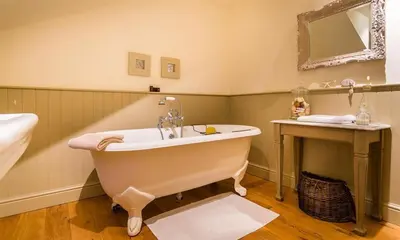 a bathroom with a bath tub and a sink at Thimble Hall in Grasmere
