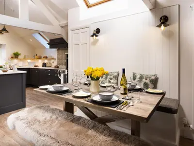a dining room with a wooden table and a kitchen at Tilly's Cottage in Grasmere