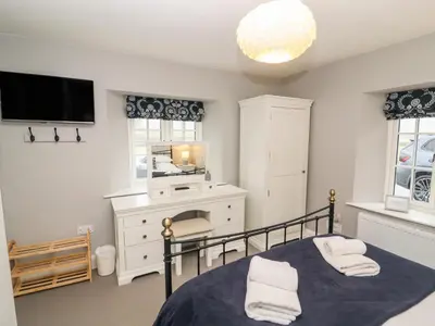 a bedroom with a bed and a desk and a mirror at Tilly's Cottage in Grasmere