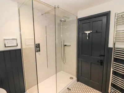 a glass shower with a black door in a bathroom at Tilly's Cottage in Grasmere