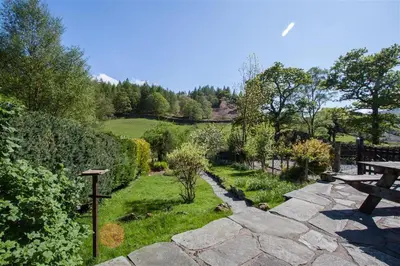 a garden with a stone pathway and a picnic table at Robins Nest in Coniston
