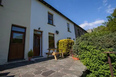 a white house with a wooden door and a bench at Robins Nest in Coniston