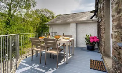 a patio with a table and chairs on a balcony at Riverville in Grasmere