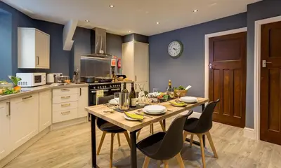 a kitchen with a table with chairs and a clock on the wall at Riverville in Grasmere