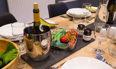 a table with a bottle of wine and a bowl of vegetables at Riverville in Grasmere