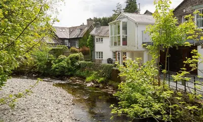 a house with a stream in front of a house at Riverville in Grasmere