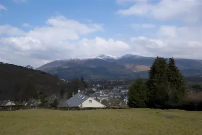 a white house on a hill with mountains in the background at Bandol in Braithwaite