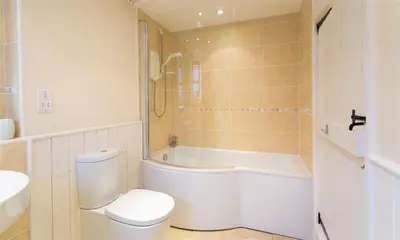 a bathroom with a toilet and a tub and a sink at Thirlmere Cottage in Keswick