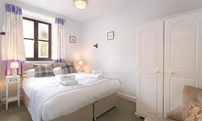 a bedroom with a large white bed and a chair at Thirlmere Cottage in Keswick