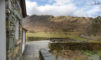 a stone building with a view of a mountain at Thirlmere Cottage in Keswick