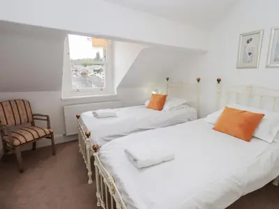 two beds in a room with a chair and a window at Number Twenty in Keswick