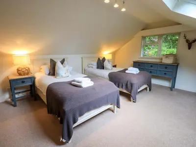 a bedroom with two beds and two tables and a window at Underheron in Grasmere