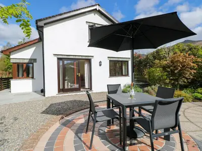 a black table with chairs and an umbrella on a patio at Rowanberry Cottage in Grasmere