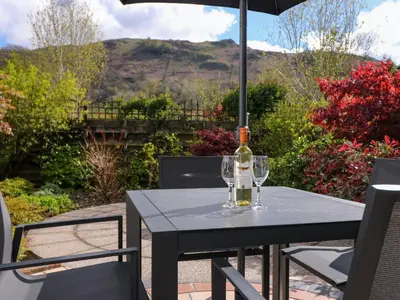 a bottle of wine on a table with an umbrella at Rowanberry Cottage in Grasmere