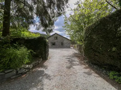 a gravel road leading to a house with a building at Rowanberry Cottage in Grasmere