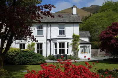 a white house with flowers in front of it at Ben House in Grasmere