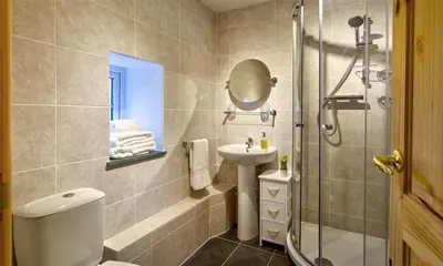 a bathroom with a shower and a toilet and a sink at Scalegill House in Cockermouth