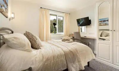 a bedroom with a bed and a tv and a window at Heathfield in Keswick