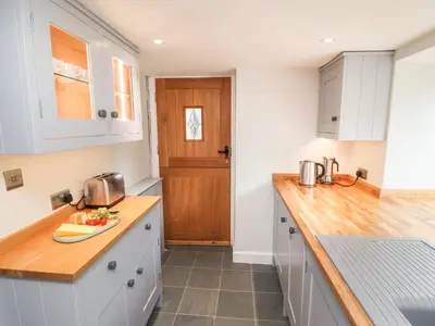 a kitchen with white cabinets and a wooden counter top at Weir Cottage in Ambleside