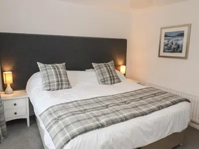 a bedroom with a large white bed with a black headboard at Weir Cottage in Ambleside
