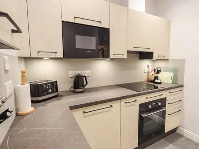 a kitchen with white cabinets and a black appliance at Easedale in Grasmere