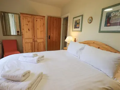 a bedroom with a large white bed with towels on it at Holme Ground Cottage in Coniston