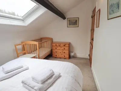 a bedroom with a white bed and a crib at Holme Ground Cottage in Coniston
