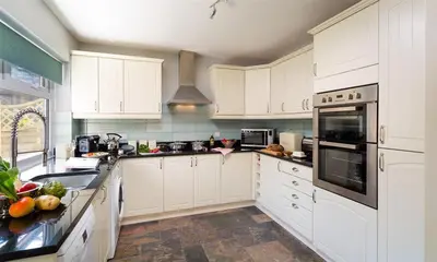 a white kitchen with white cabinets and appliances at Little Leveret Cottage in Keswick