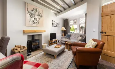 a living room with leather furniture and a fireplace at Little Leveret Cottage in Keswick
