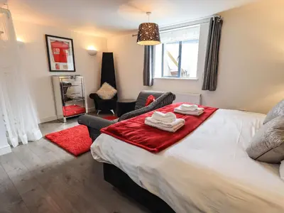 a bedroom with a bed with a red blanket on it at Le Chalet in Elterwater
