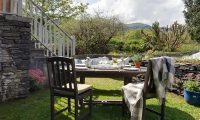 a table and two chairs in a yard with a table and chairs at Glen View Cottage in Ambleside