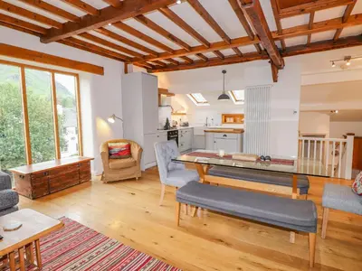 a living room with a table and a kitchen at Glen View Cottage in Ambleside