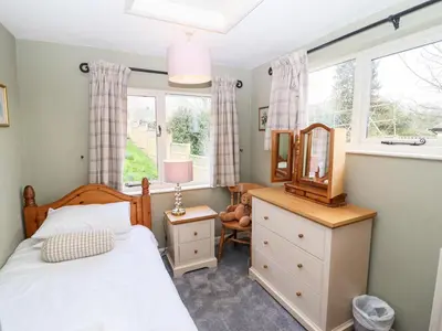 a bedroom with a bed and a mirror and a window at Gunpowder Cottage in Elterwater