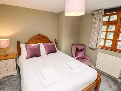 a bedroom with a bed and a chair at Gunpowder Cottage in Elterwater