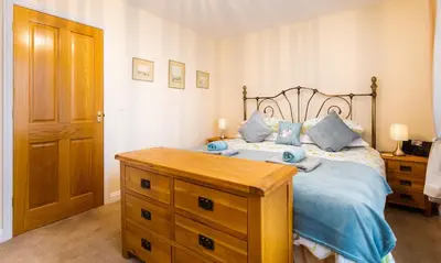 a bedroom with a bed and a wooden dresser at Artists Hideaway in Portinscale