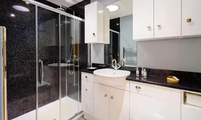 a white bathroom with a shower and a sink at Artists Hideaway in Portinscale