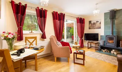 a living room with red curtains and a table at Artists Hideaway in Portinscale