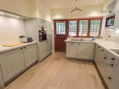 a large kitchen with white cabinets and wooden floors at Croft in Grasmere
