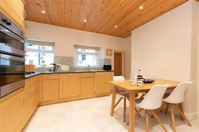 a kitchen with a wooden table and white chairs at Gable End in Keswick