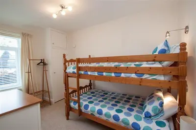 a bedroom with two bunk beds and a kitchen at Gable End in Keswick