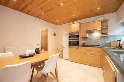 a kitchen with a wooden table and white chairs at Gable End in Keswick
