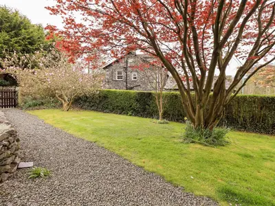 a garden with a tree and a house in the background at Holmdale in Ambleside